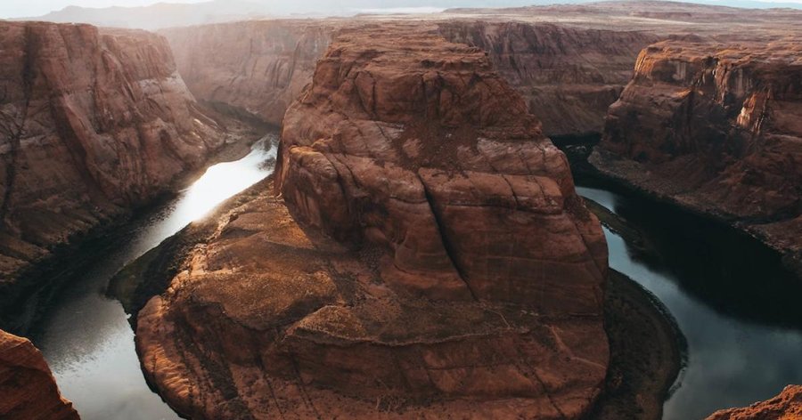 A winding river surrounded by layered sandstone canyon cliffs